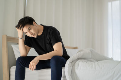 Young woman sitting on bed at home