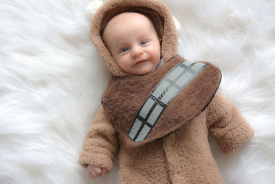 Portrait of cute baby boy in warm clothing lying down on fur