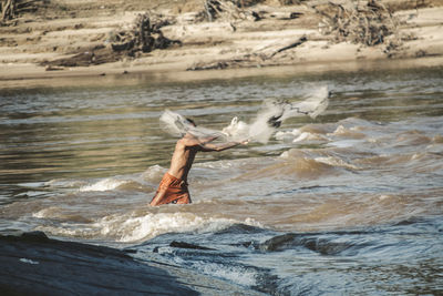 Fisherman casting fishing net in sea