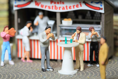 Close-up of figurines eating by food stall