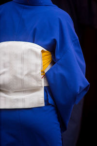 Rear view of man standing against blue background