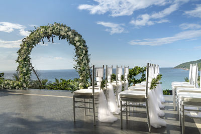 Chairs and table by sea against sky