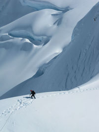 Unrecognizable climber on a mountaineering rope team ascends a ridge in the alaska range