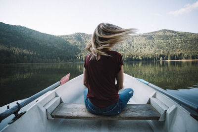Rear view of woman sitting on boat against lake