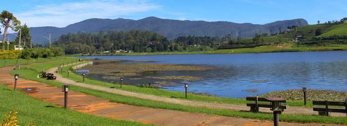 Scenic view of field by lake against sky