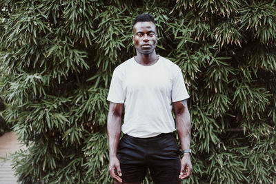 Male athlete standing against leaves