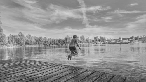 Rear view of boy jumping in lake