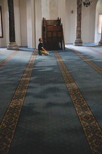 Rear view of woman walking on tiled floor in building