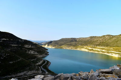 Scenic view of sea and mountains against clear blue sky