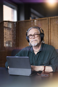 Portrait of senior man with headphones using tablet