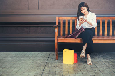 Woman looking away while standing against wall