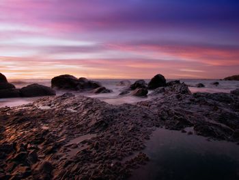 Scenic view of rocky shore at sunset