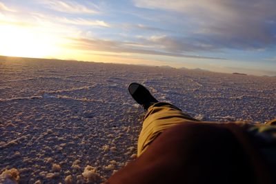 Low section of person on land against sky during sunset