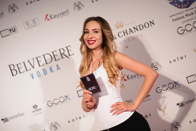 Young woman standing against white wall