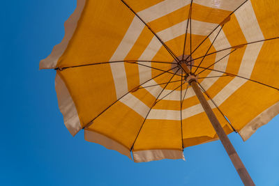 Low angle view of yellow umbrella against clear blue sky