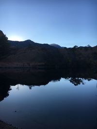 Scenic view of lake and mountains against clear blue sky