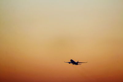 Low angle view of silhouette airplane against clear sky during sunset