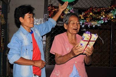 Close-up of senoir woman getting a gift box at night.