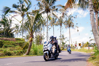 Rear view of man riding motor scooter on road
