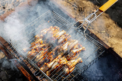 Bbq chicken legs roasting on coals in the garden.