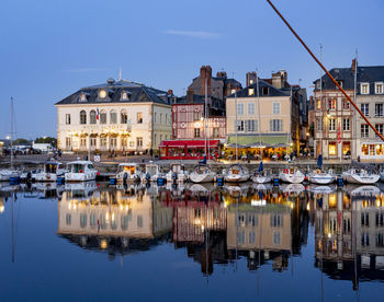 Sailboats moored on canal by buildings against sky