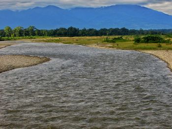 Scenic view of river by mountains against sky