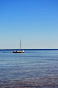 Sailboat in sea against clear blue sky