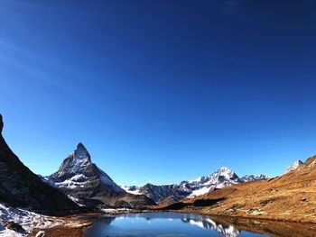 Scenic view of snowcapped mountains against clear blue sky