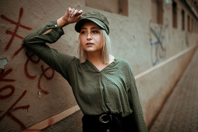 Portrait of beautiful young woman standing against graffiti wall