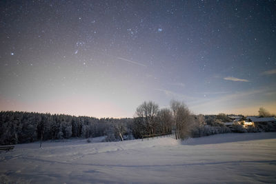 Snow covered land against sky at night