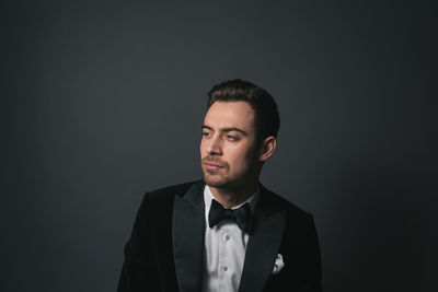 Portrait of young man standing against black background