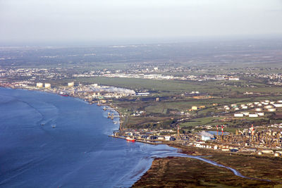 High angle view of cityscape by sea against sky