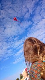 Rear view of girl flying kite against sky