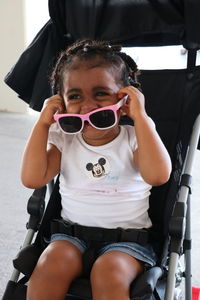 Close-up of baby girl holding sunglasses while sitting in stroller