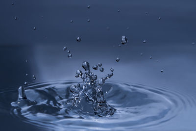 Close-up of splashing water drops causing wavy water surface