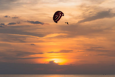 Sihouette paramotor pilot with a sunset sea scape as a background