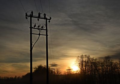 Low angle view of silhouette electricity pylon against sky during sunset