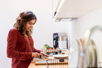 Smiling woman preparing food in kitchen at home