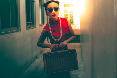 Young woman wearing sunglasses standing against wall