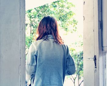 Rear view of woman standing against window