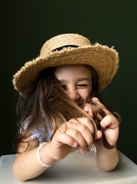 Close-up of cute girl wearing hat against black background