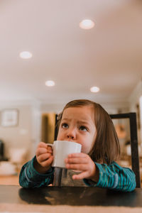 Close-up of girl holding drink at home