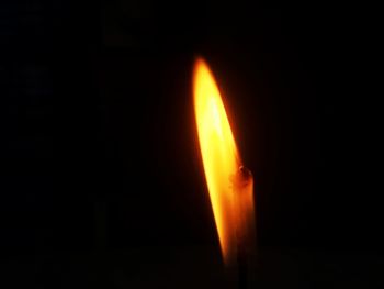 Close-up of illuminated candle against black background