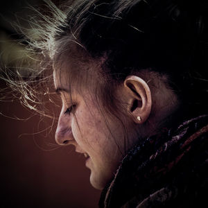 Close-up side view of young woman with messy hair outdoors