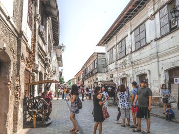 People walking on street amidst buildings in city