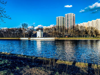 Scenic view of lake by buildings against blue sky