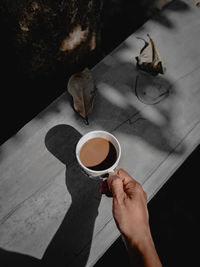 Cropped hand of woman holding coffee on table