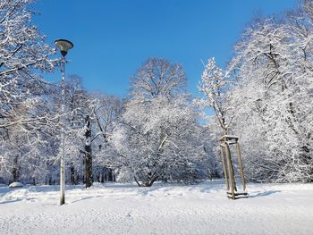 Frozen trees on field against sky during winter