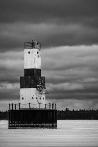 Lighthouse by sea against sky