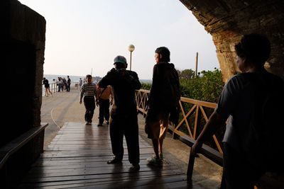 Rear view of people walking on bridge